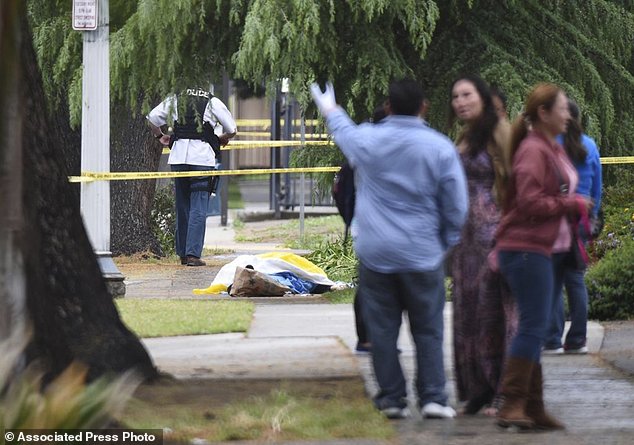 Evacuated office workers stand by, with a deceased shooting victim down on the sidewalk Tuesday